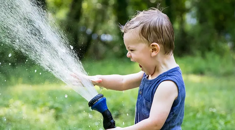 Boy playing with a water hose