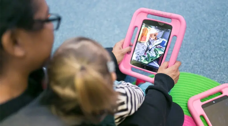 Practitioner using iPad with child in nursery