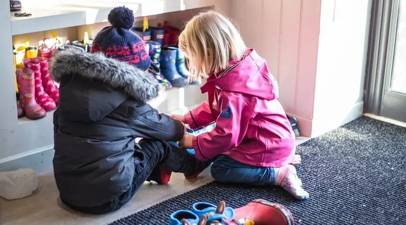 Two kids dressing up warm before heading out to play