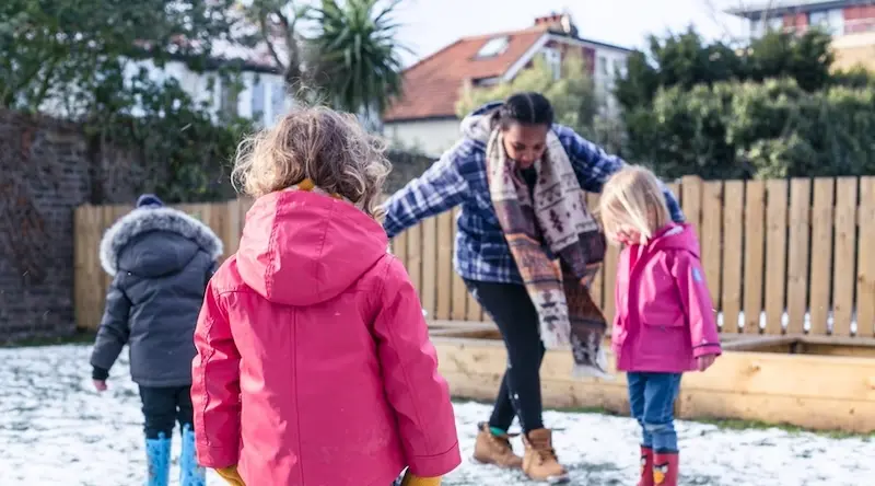 woman playing in the snow with 3 kids