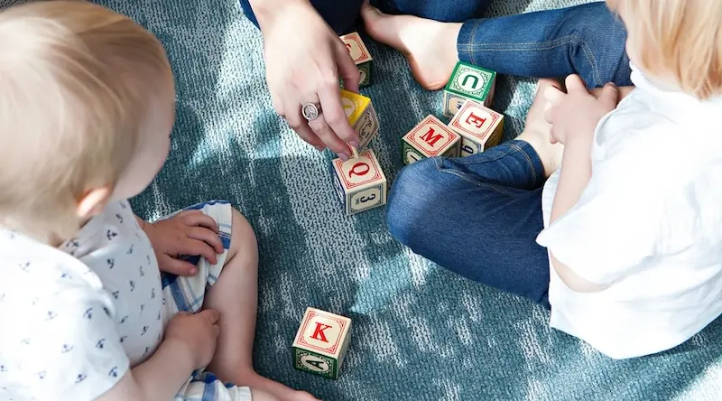 Educator playing with kids with wooden cubes
