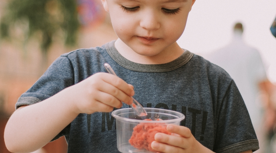An early years child eats some dessert in a nursery