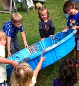 A couple of kids playing with a small swimming pool in a garden