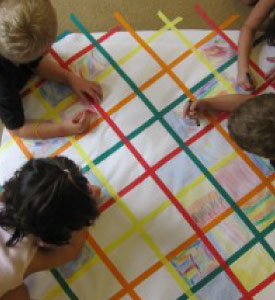 Kids colouring a sheet of paper on the floor