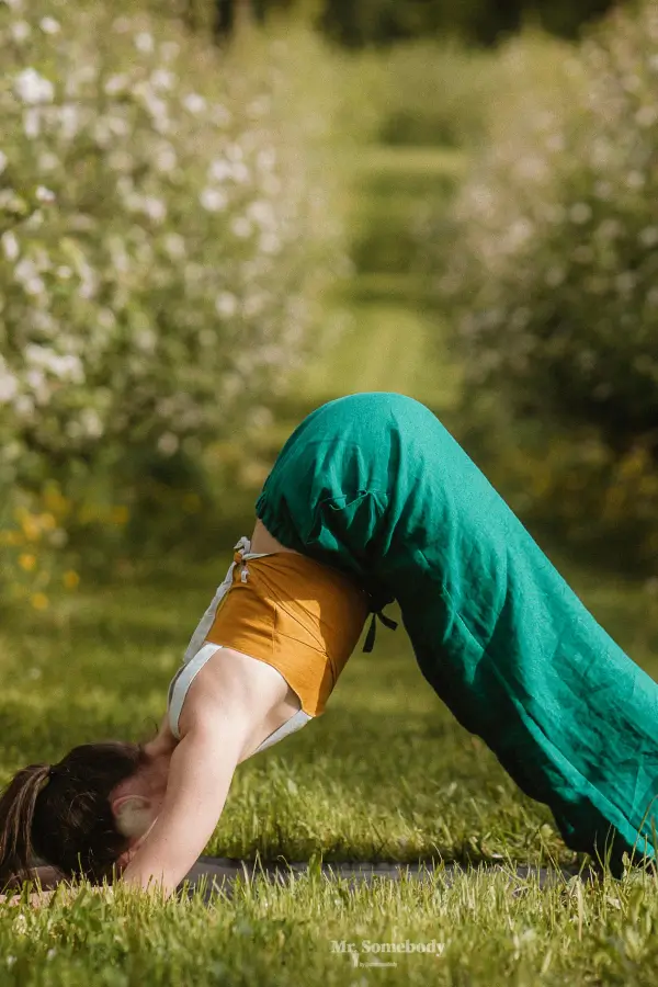 Kid in green trousers doing a yoga pose in nature