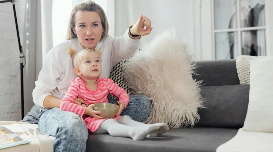 mother and young girl watching tv together