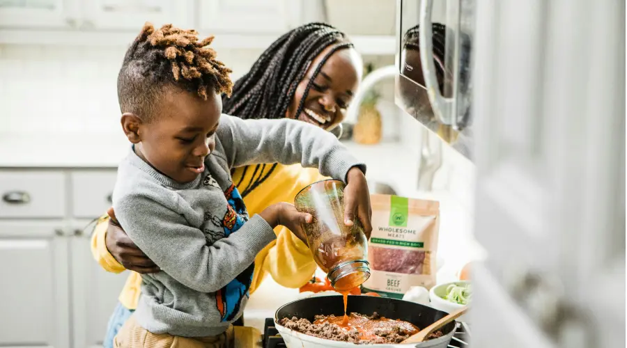 a mom and young boy cooking at home