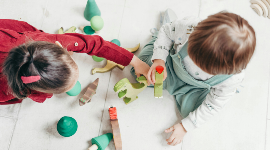 a girl and a boy playing with wooden toys