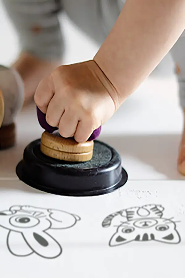 A child's hand stamps ink on a paper