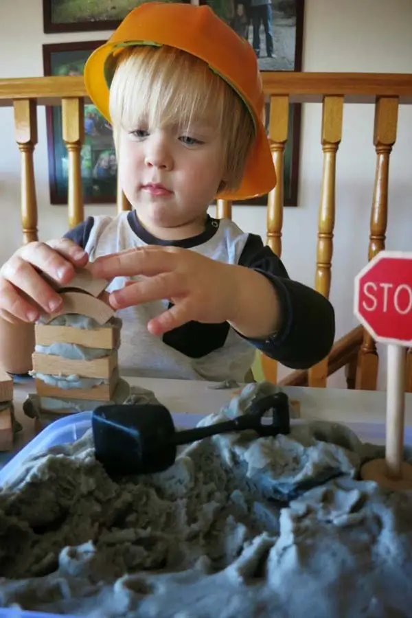 Boy with yellow helmet engaged in a bricklaying activity