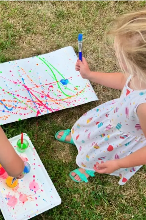 Girl drawing with splatter paint outdoors