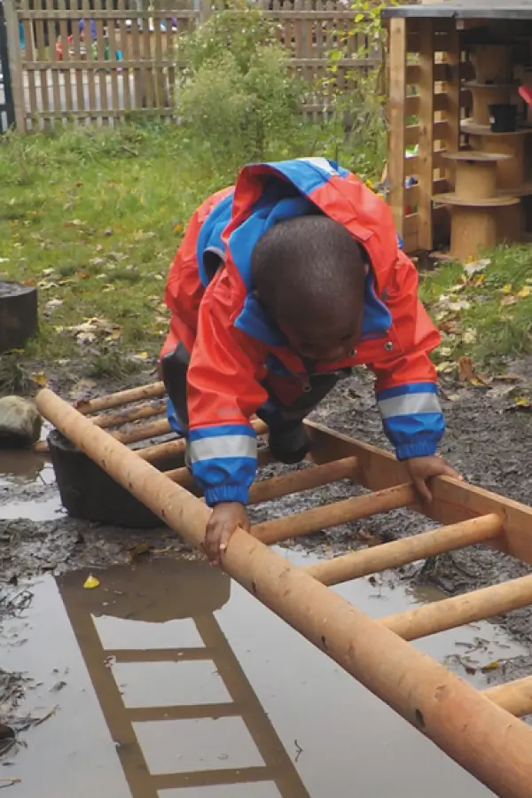 child crossing over a puddle by using a ladder