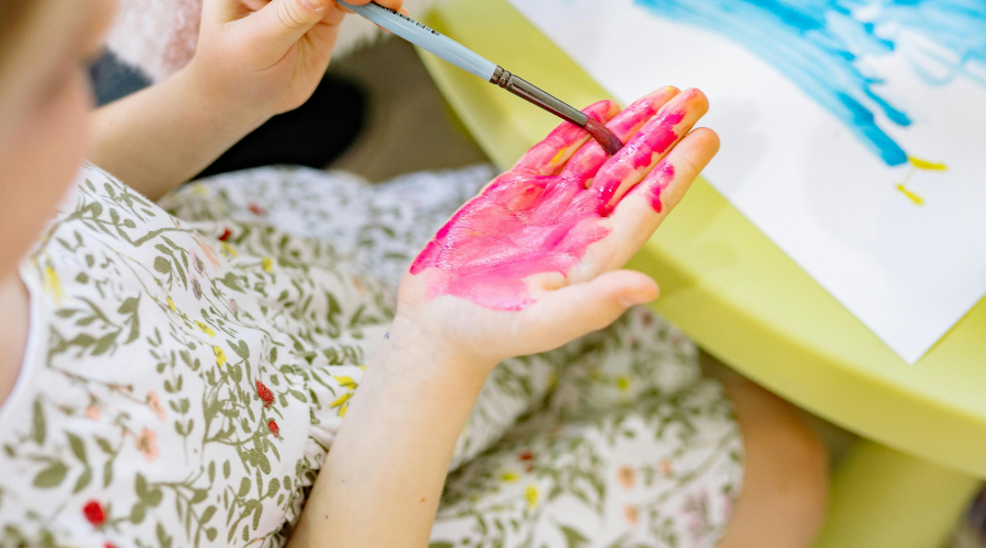 preschool girl playing with paint on her hands