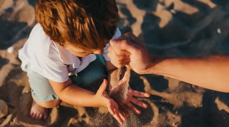 Boy playing in the sand on the beach at sunset