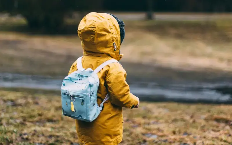 young child outside in nature with a backpack