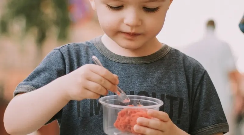 An early years child eats some dessert in a nursery