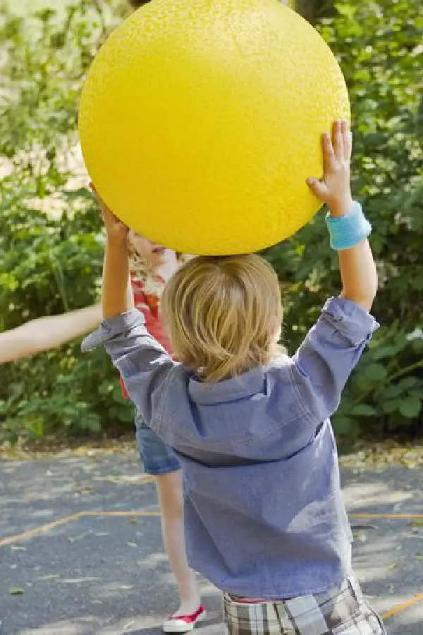 Child holding a yellow ball overhead