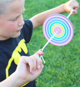 A kid spinning a paper circle on a string.