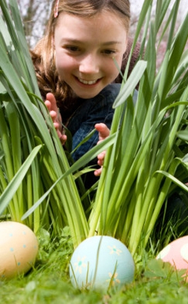 girl looking through grass at easter egg