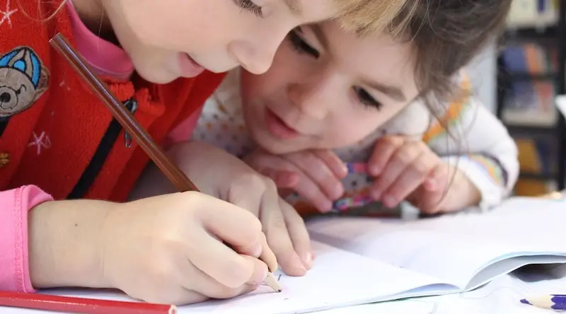 two young girls drawing with brown pencil