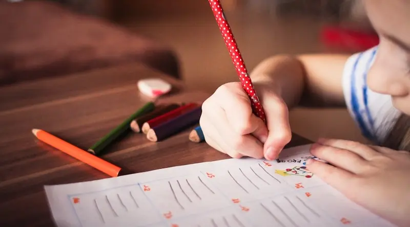 girl writing with red polka-dot pencil