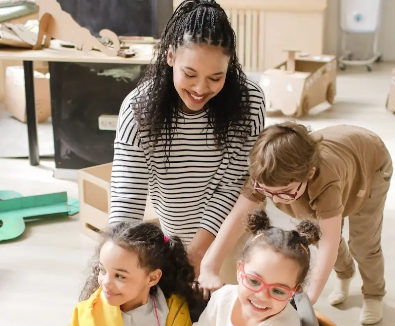 An Early Years educator plays with three young children in a nursery
