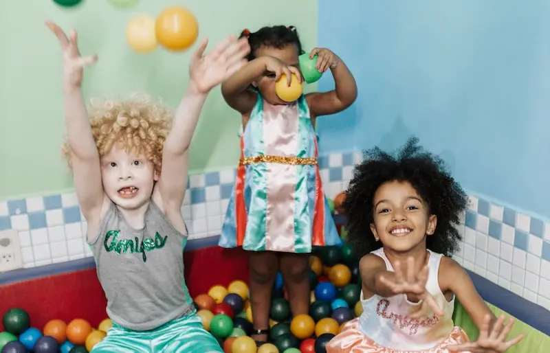 Three Early Years children play in a ball pool.