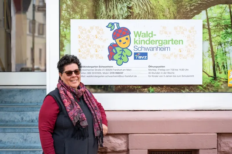 Tina vom Waldkindergarten Schanheim posiert vor dem Kindergarten in einem roten Oberteil und einem bunten Schal