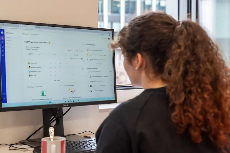 Erzieherinnen, die an einem Desktop-Computer arbeiten, auf dem die Famly-App auf dem Startbildschirm geöffnet ist.