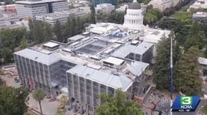 Aerial view of a construction site around a white domed capitol building in a city park.