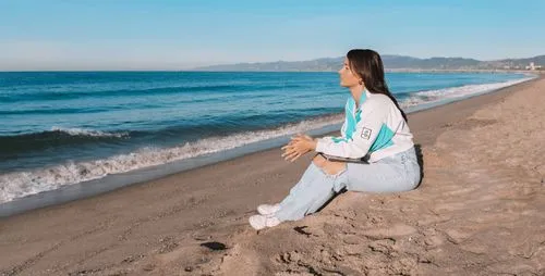 Maddie Nieman, also called Madz, sitting on the beach looking at the waves with her laptop