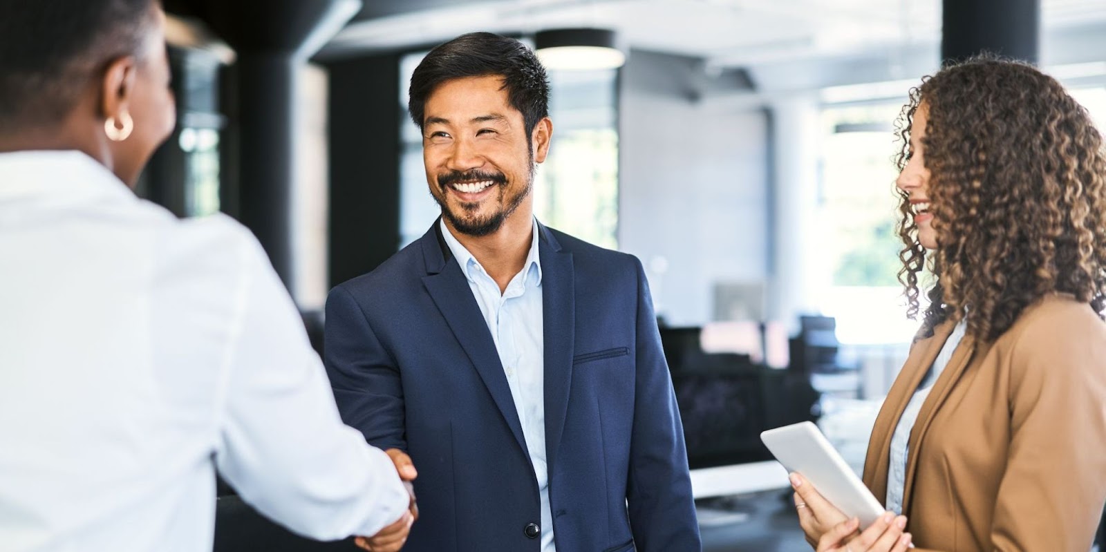 A man and 2 women in business attire talking.