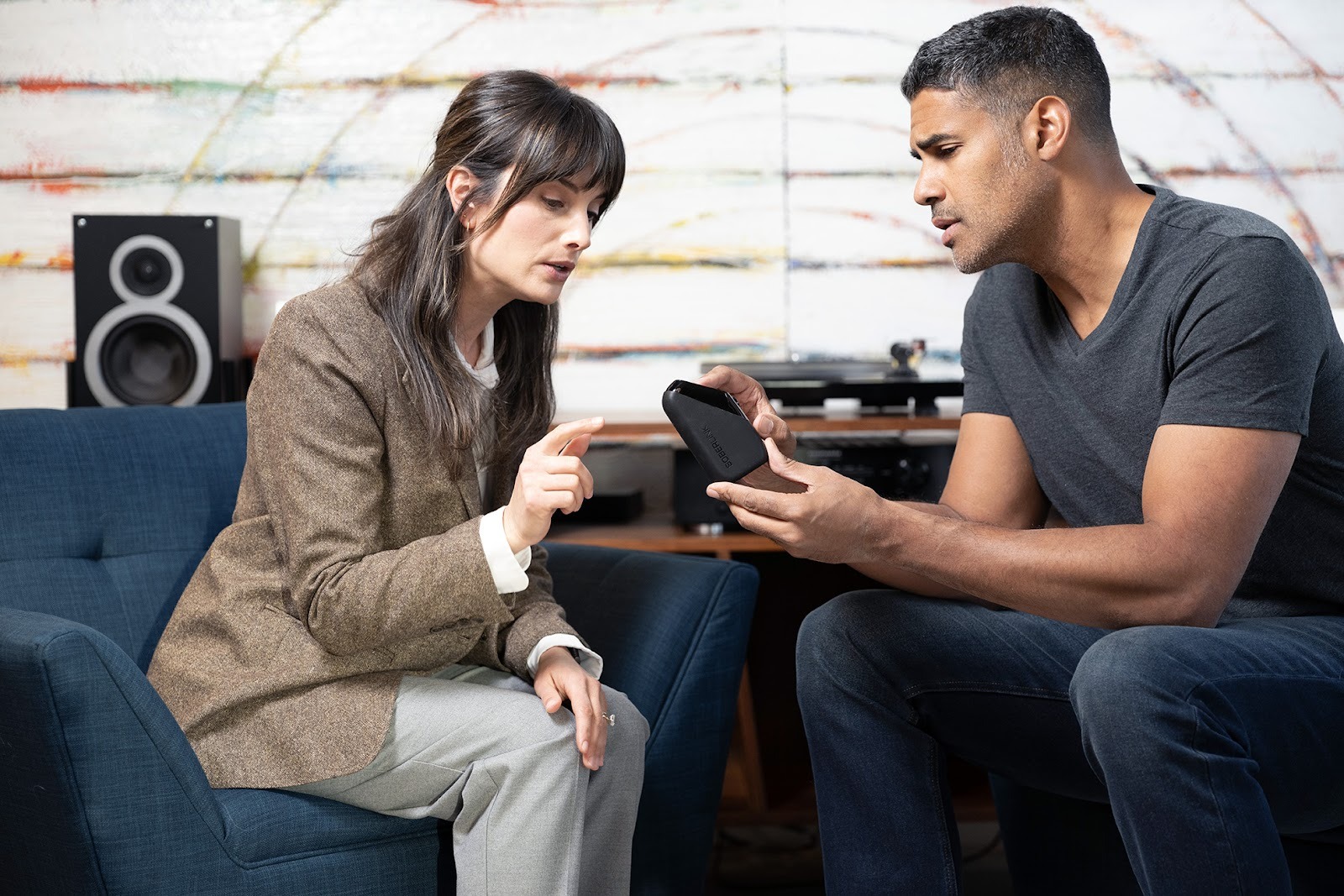 A man and woman having a discussion and the man is holding a Soberlink device. 