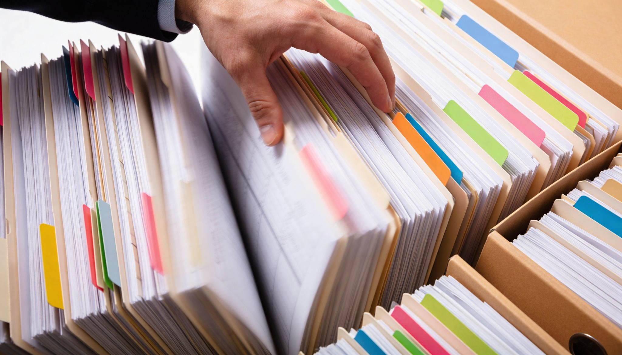 A hand looking through files.