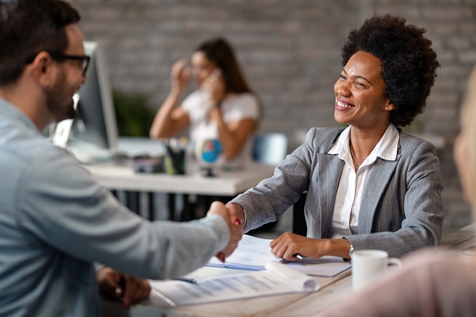 A man and woman shaking hands in a business meeting.