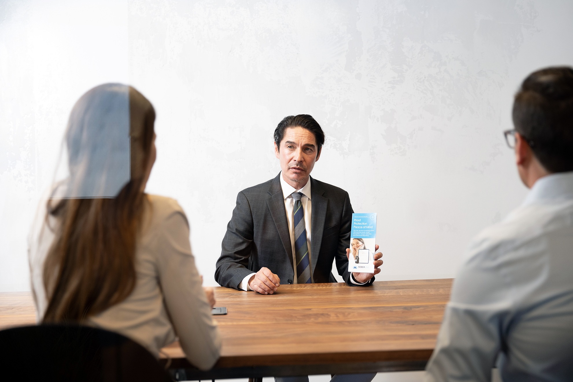 A law professional showing a man and woman a pamphlet.j