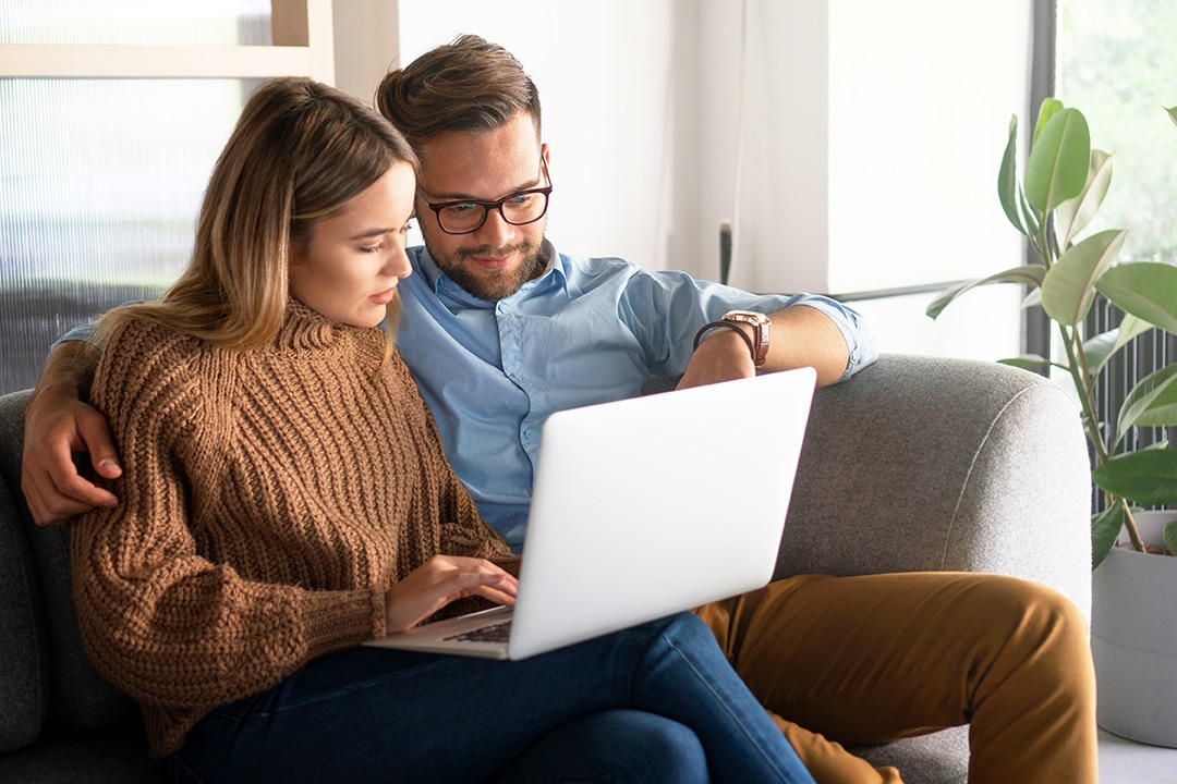 A man and woman looking at a laptop.