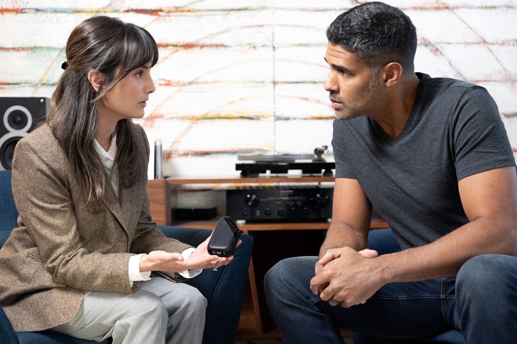 A woman is holding a Soberlink device while in discussion with a man.