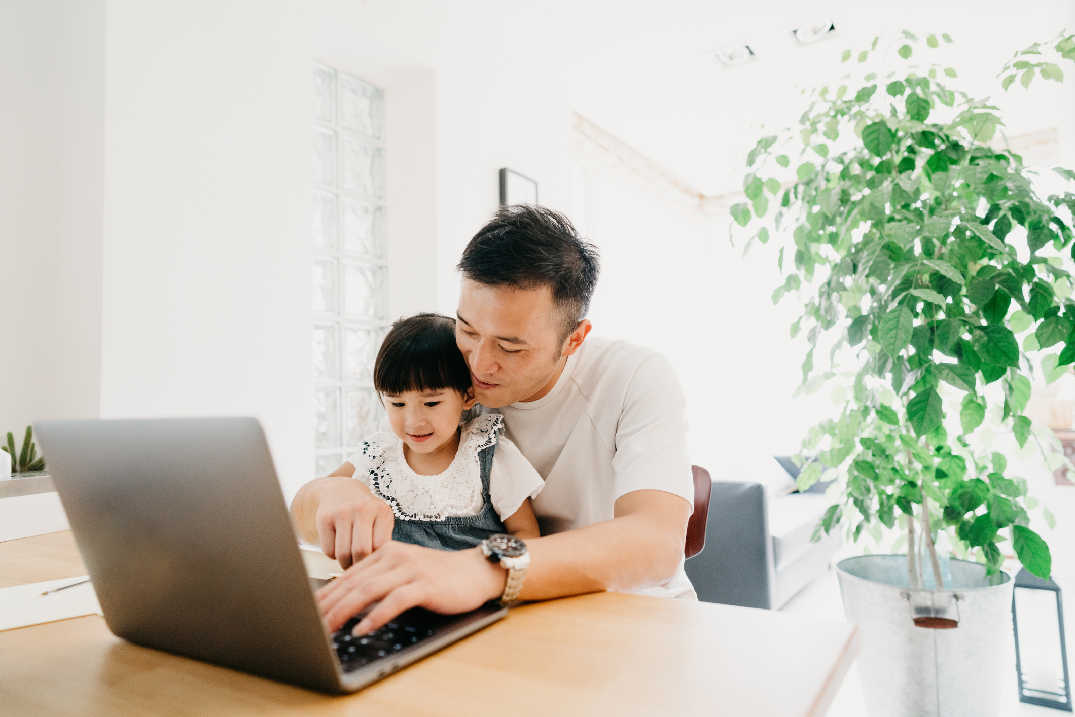 Dad teaching daughter to type on laptop