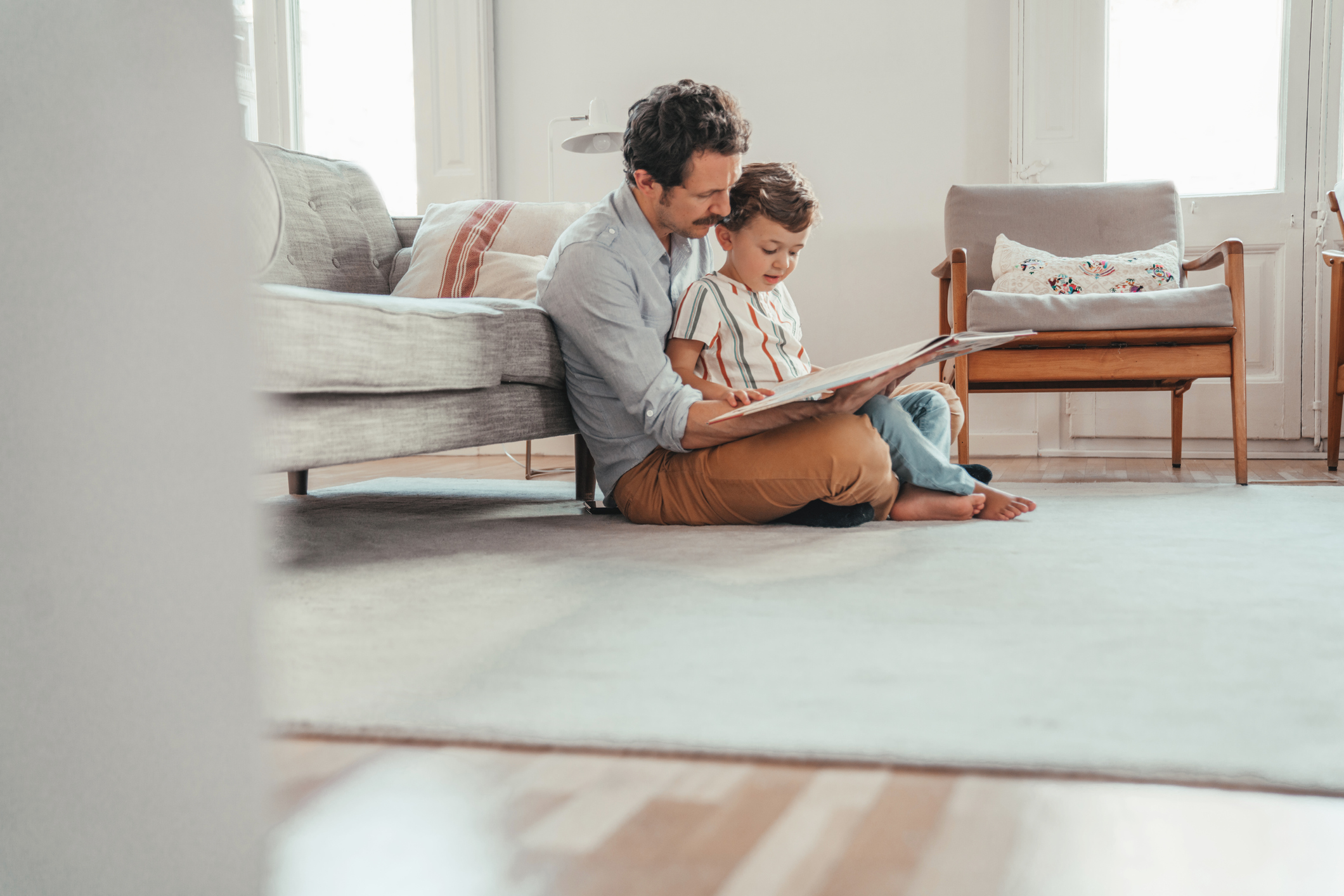 Father reading to his son on the floor of their living room