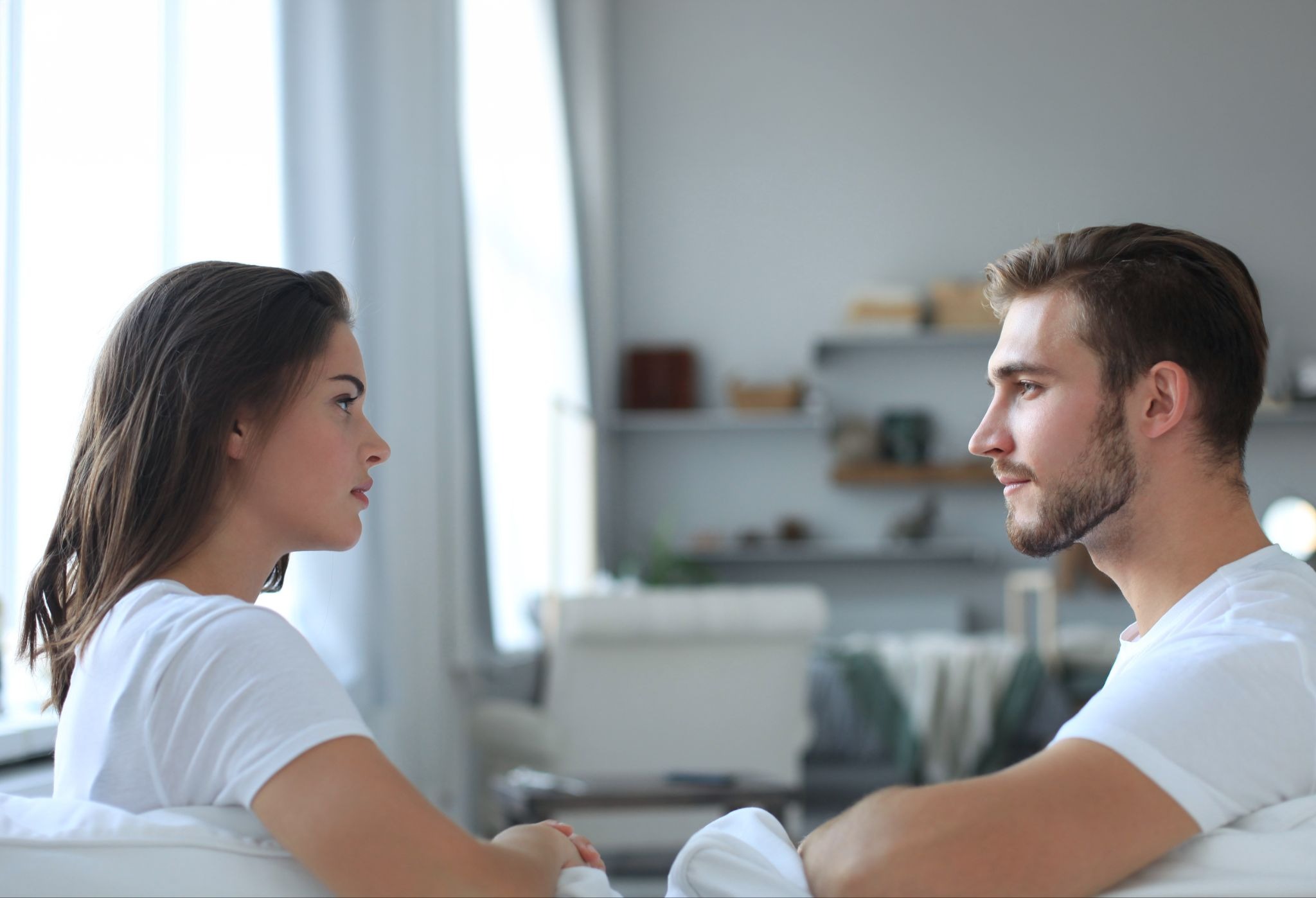 A man and woman sitting on a couch and looking at each other.