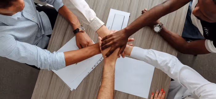 Employees with their hands reaching in the middle of a table