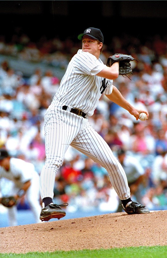 Man in baseball uniform pitching from mound