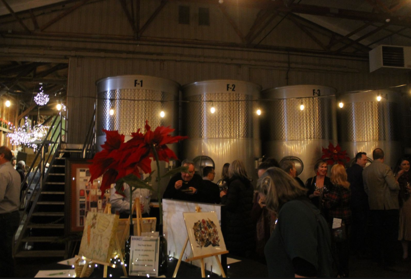 People look at silent auction items in a tasting room.