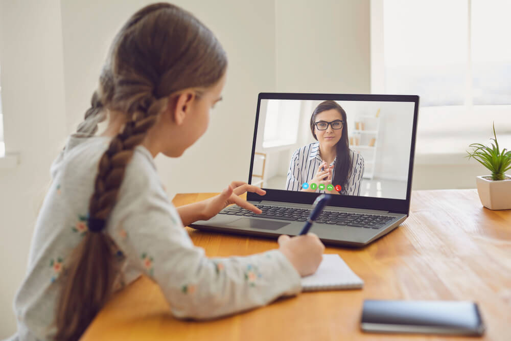 Child taking livestreamed online class in public school classroom