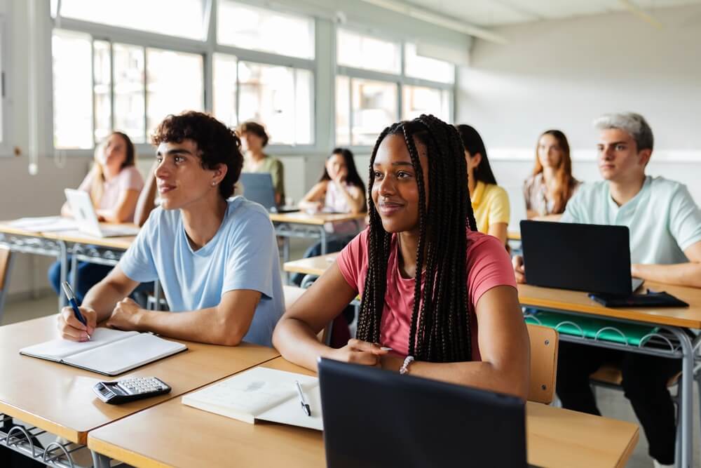 A classroom of happy high school students with laptops during a lesson
