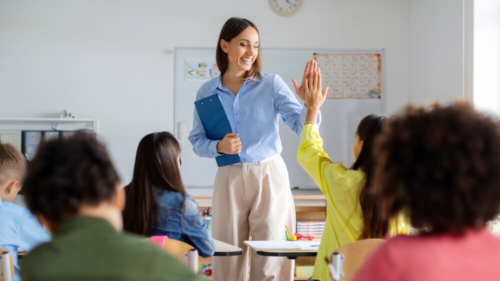 A cheerful teacher giving a student a high-five in a small group class.