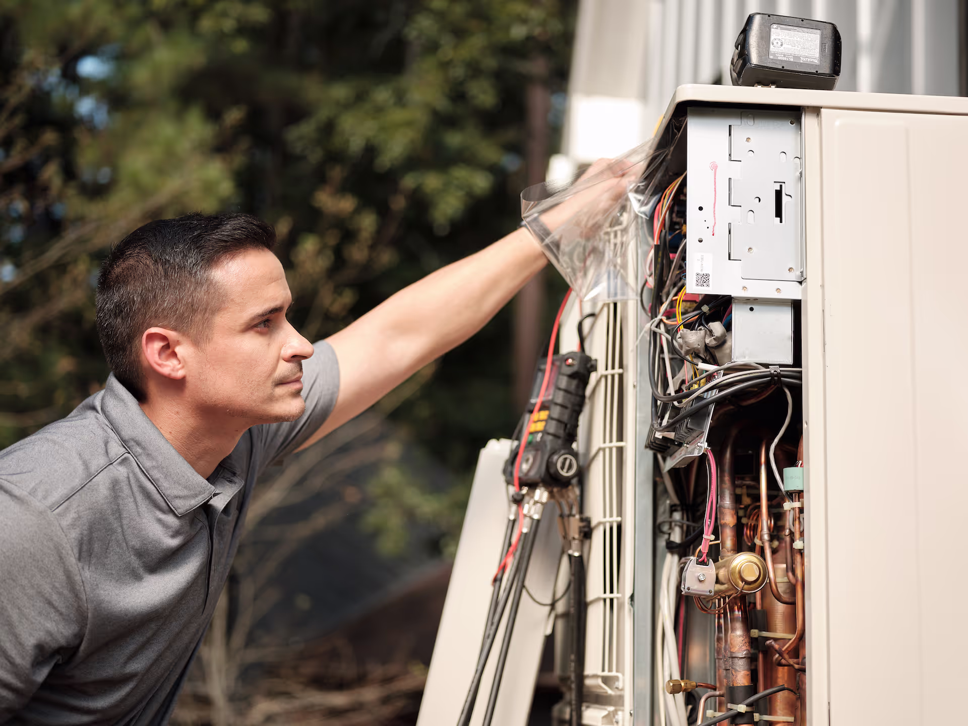 Technician inspecting outdoor HVAC unit components