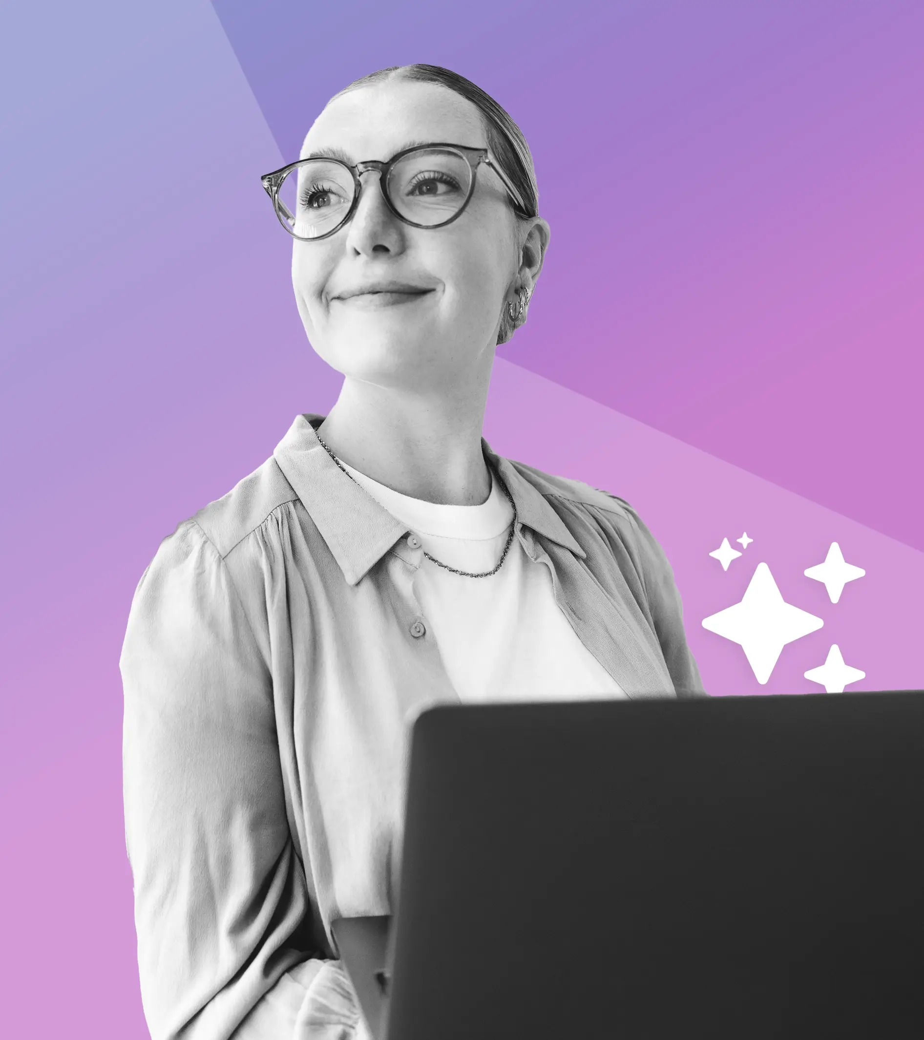 A photo of a woman smiling while using her laptop.