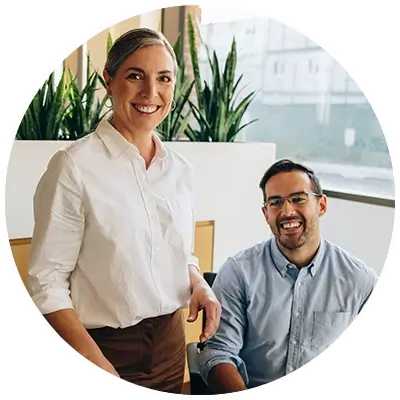 Man and woman in an office smiling at a laptop